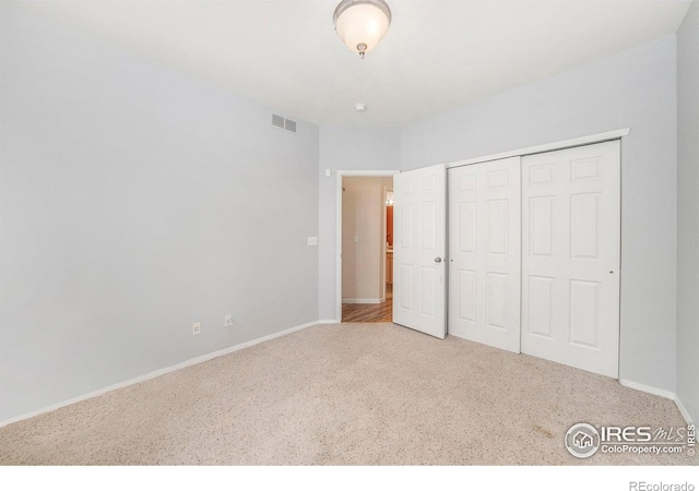 unfurnished bedroom with carpet floors, baseboards, and a closet