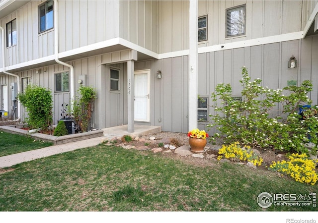 doorway to property featuring a lawn and board and batten siding