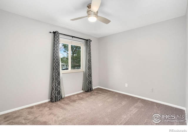carpeted spare room with ceiling fan and baseboards