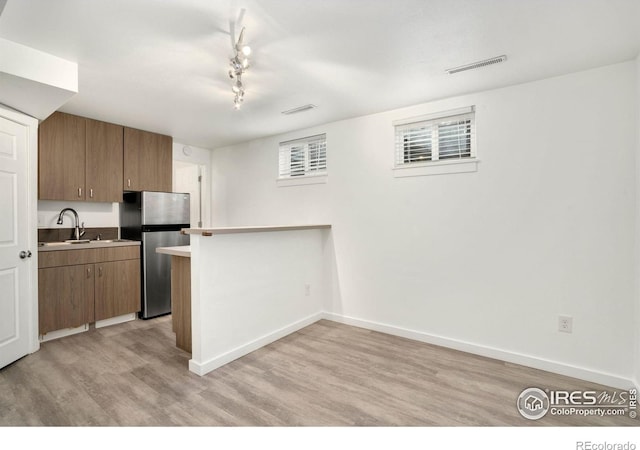 kitchen featuring light wood finished floors, freestanding refrigerator, a peninsula, baseboards, and visible vents