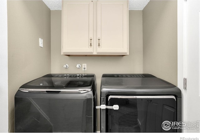 laundry room featuring separate washer and dryer, a textured ceiling, and cabinet space