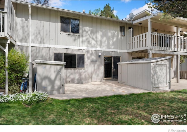 back of house with a storage shed, board and batten siding, an outbuilding, a patio area, and a yard
