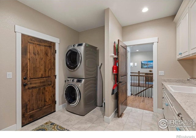 1603 Plank Ln, Fort Collins, CO 80524 - laundry room with baseboards, stacked washer / drying machine, a sink, cabinet space, and light tile patterned floors