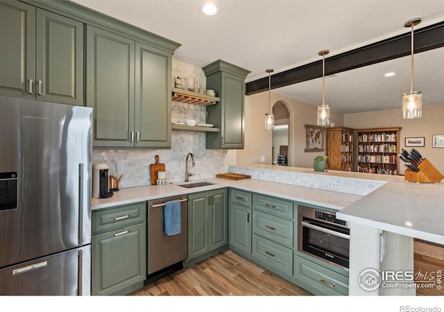 1603 Plank Ln, Fort Collins, CO 80524 - kitchen with appliances with stainless steel finishes, tasteful backsplash, light wood-type flooring, a sink, and green cabinetry