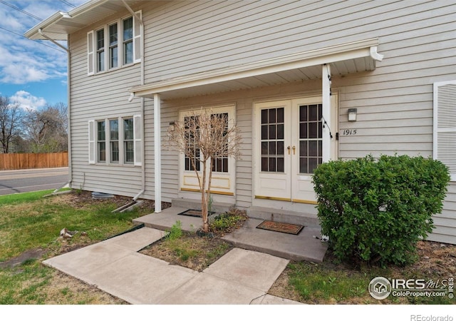 view of exterior entry featuring french doors and fence