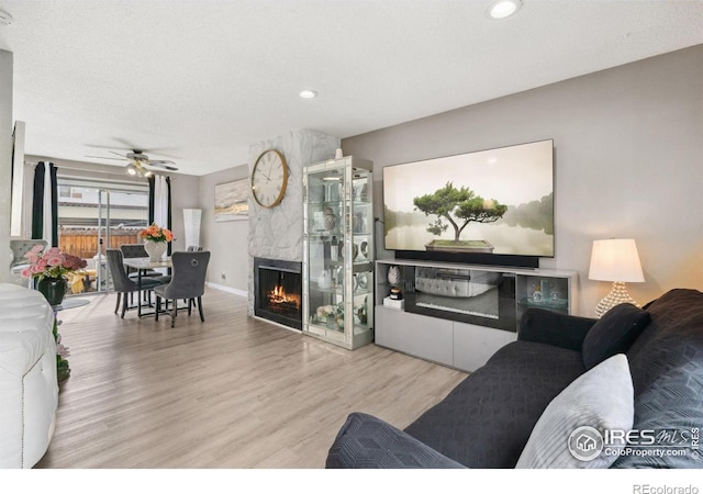 living area featuring ceiling fan, a fireplace, recessed lighting, baseboards, and wood finished floors