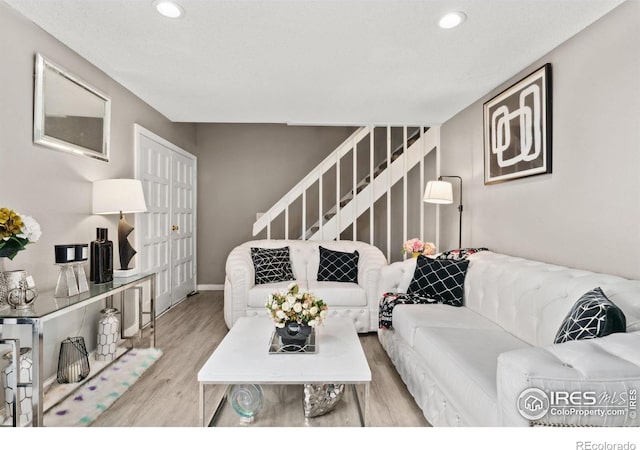 living area with recessed lighting, baseboards, wood finished floors, and stairway