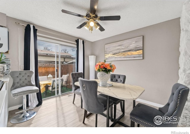 dining area featuring a textured ceiling, ceiling fan, baseboards, and wood finished floors