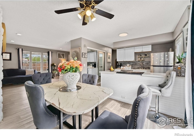 dining room with recessed lighting, a ceiling fan, light wood finished floors, and a textured ceiling