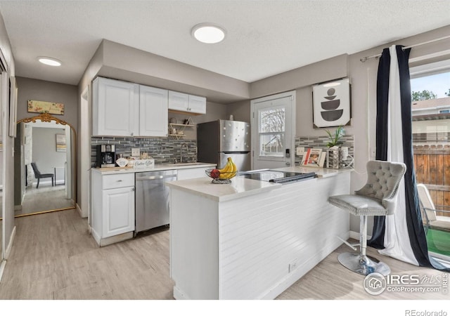 kitchen with light countertops, light wood finished floors, a peninsula, and stainless steel appliances