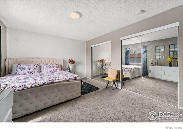 carpeted bedroom featuring a textured ceiling and two closets