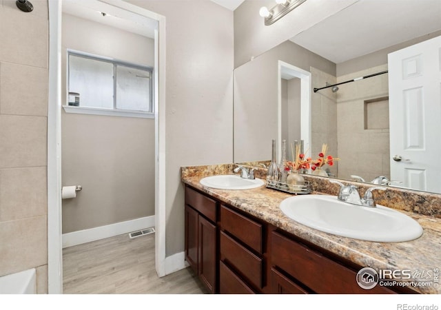 full bath featuring double vanity, visible vents, a sink, and wood finished floors