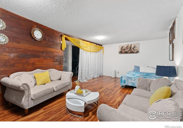 living area featuring wood walls, a textured ceiling, and wood finished floors