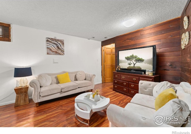 living room with a textured ceiling, visible vents, wood walls, wood finished floors, and baseboards