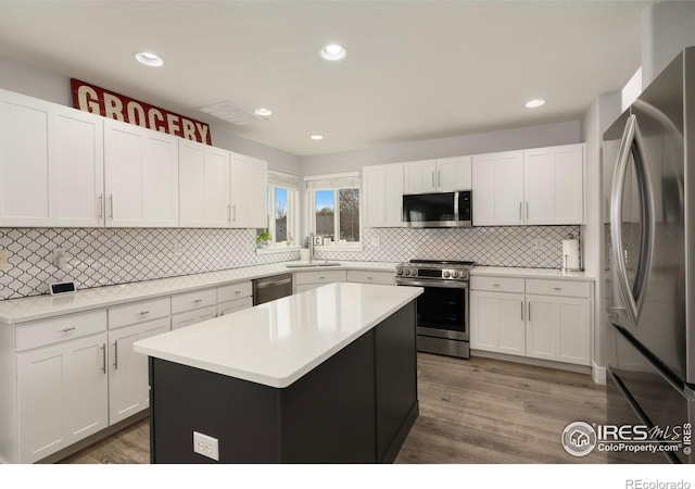 4400 Red Fox Ct, Loveland, CO 80537 - kitchen featuring wood finished floors, appliances with stainless steel finishes, a sink, and tasteful backsplash