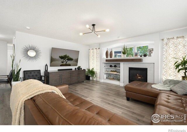4400 Red Fox Ct, Loveland, CO 80537 - living room with a glass covered fireplace, wood finished floors, and a notable chandelier