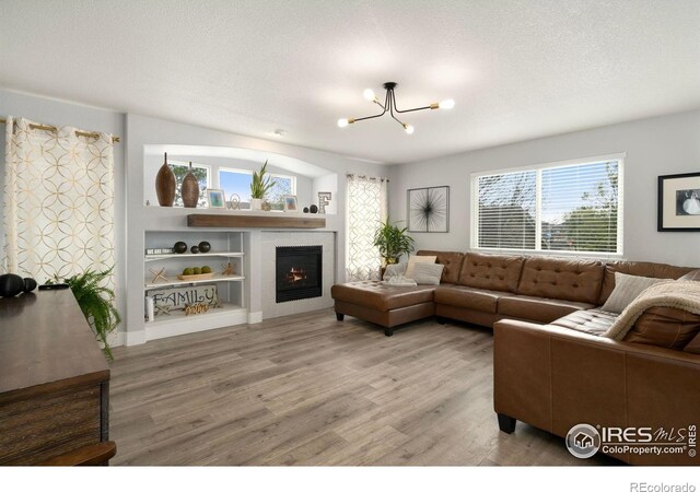 4400 Red Fox Ct, Loveland, CO 80537 - living area featuring a lit fireplace, a textured ceiling, built in shelves, a chandelier, and light wood-style floors