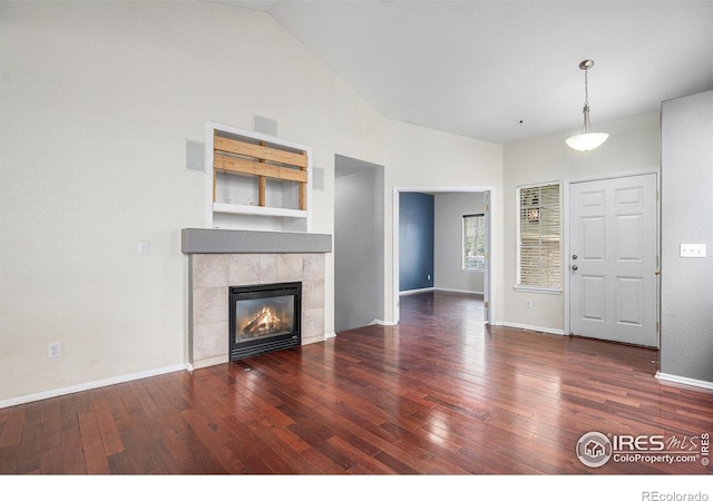 unfurnished living room featuring a tiled fireplace, baseboards, visible vents, and hardwood / wood-style flooring
