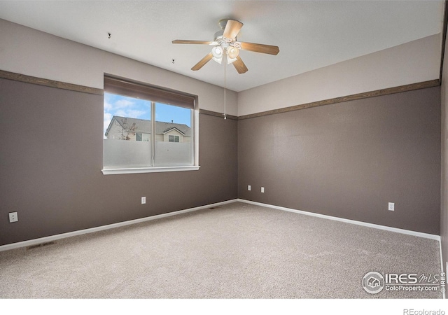 carpeted empty room with visible vents, a ceiling fan, and baseboards