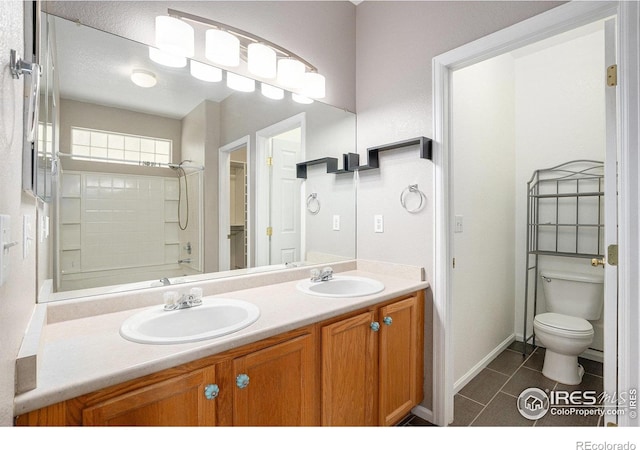 bathroom featuring a sink, tile patterned flooring, toilet, and double vanity