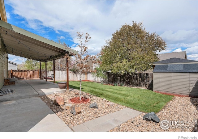view of yard with a fenced backyard, a storage unit, a patio, and an outbuilding