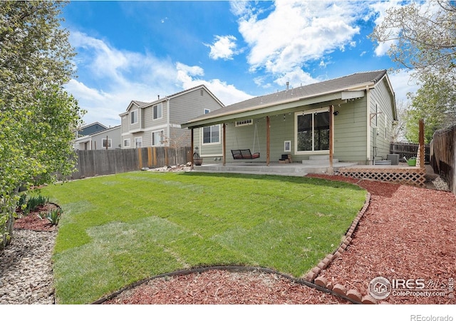 rear view of property featuring a yard, a patio, and a fenced backyard