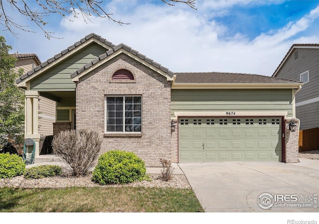 view of front of home with brick siding, a garage, driveway, and a tiled roof