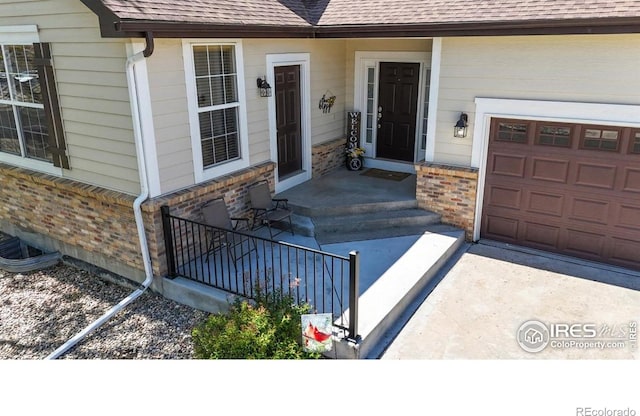 view of exterior entry with brick siding, a shingled roof, and a garage