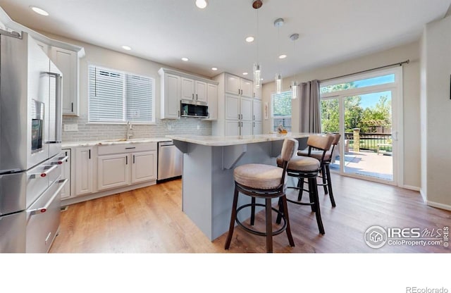 kitchen featuring appliances with stainless steel finishes, light wood-style floors, a breakfast bar area, a kitchen island, and recessed lighting