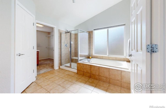 bathroom featuring tile patterned flooring, a shower stall, vaulted ceiling, a garden tub, and a walk in closet