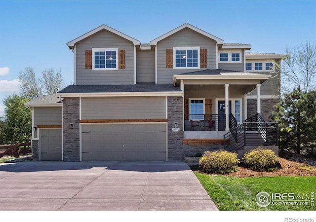 craftsman-style house featuring stone siding, a porch, an attached garage, and driveway