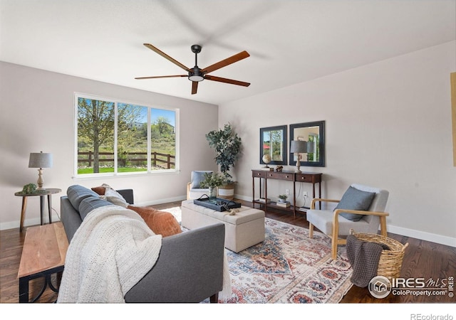 living room featuring ceiling fan, baseboards, and wood finished floors