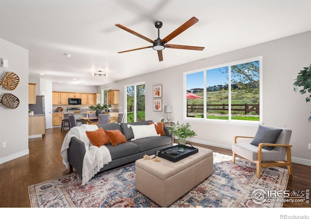 living room featuring dark wood finished floors, baseboards, and a ceiling fan