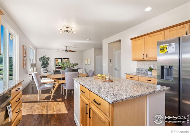 kitchen featuring dark wood-style flooring, light stone counters, open floor plan, stainless steel refrigerator with ice dispenser, and backsplash