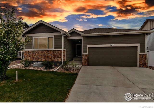 view of front of house featuring a garage, a lawn, concrete driveway, and stone siding