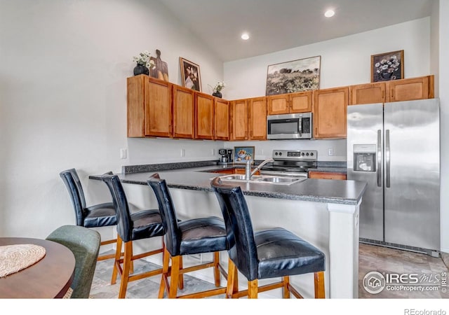 kitchen with a peninsula, dark countertops, a breakfast bar, recessed lighting, and appliances with stainless steel finishes
