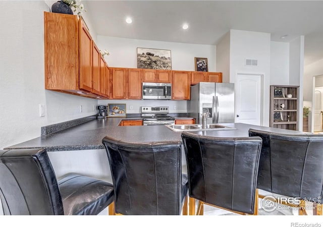 kitchen featuring dark countertops, a sink, brown cabinetry, stainless steel appliances, and visible vents