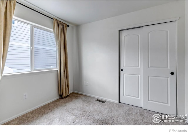 unfurnished bedroom with carpet floors, baseboards, a closet, and visible vents