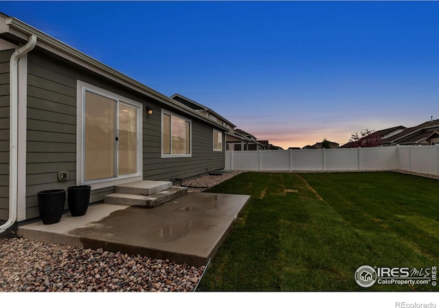 yard at dusk with a patio and a fenced backyard