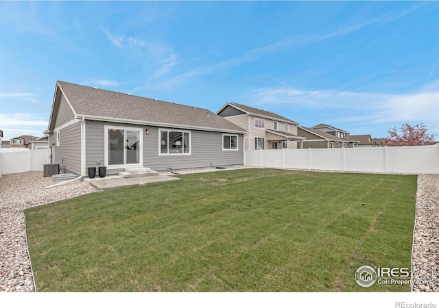 back of house with a lawn, central AC unit, a fenced backyard, and roof with shingles