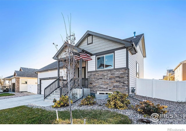 view of front of house featuring fence, an attached garage, concrete driveway, and stone siding