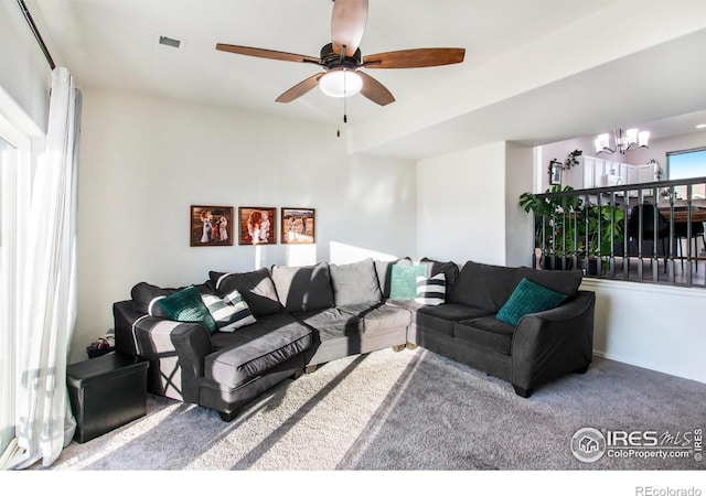 living room with visible vents, carpet flooring, and ceiling fan with notable chandelier