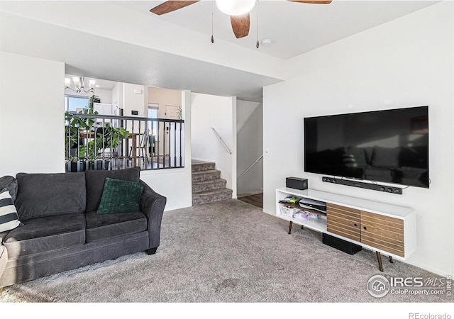 living area with carpet flooring, ceiling fan with notable chandelier, and stairway