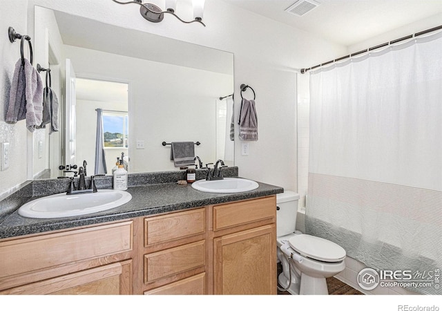 bathroom with visible vents, a sink, double vanity, and toilet