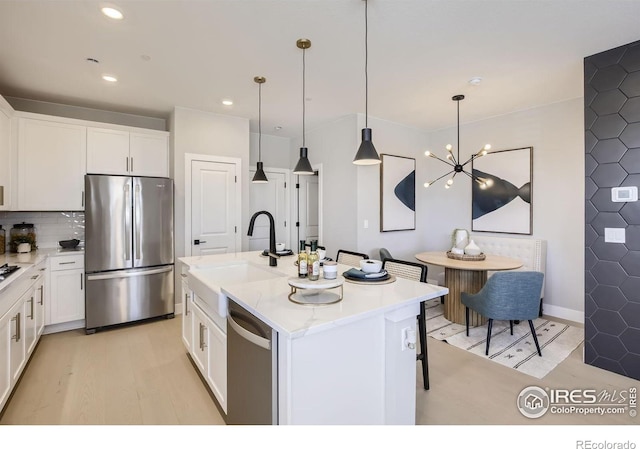 kitchen with a sink, light wood-style flooring, stainless steel appliances, and white cabinetry