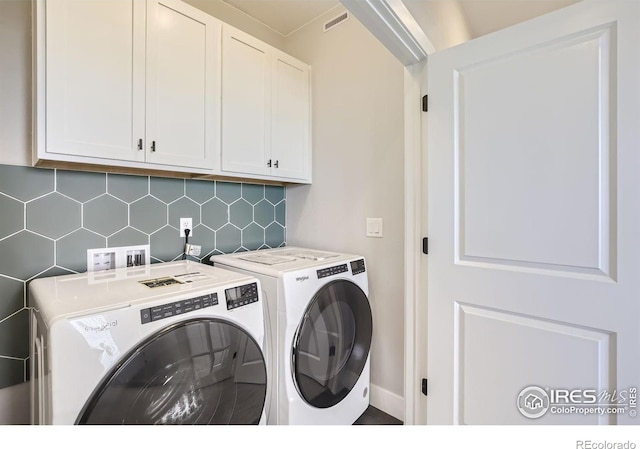 clothes washing area featuring baseboards, cabinet space, and washing machine and dryer