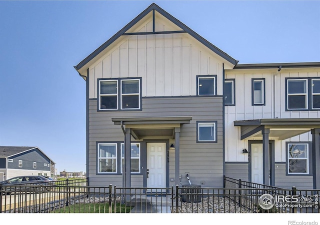 multi unit property with central air condition unit, board and batten siding, and a fenced front yard