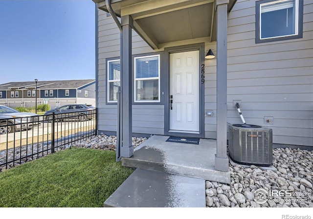 entrance to property featuring central AC and fence