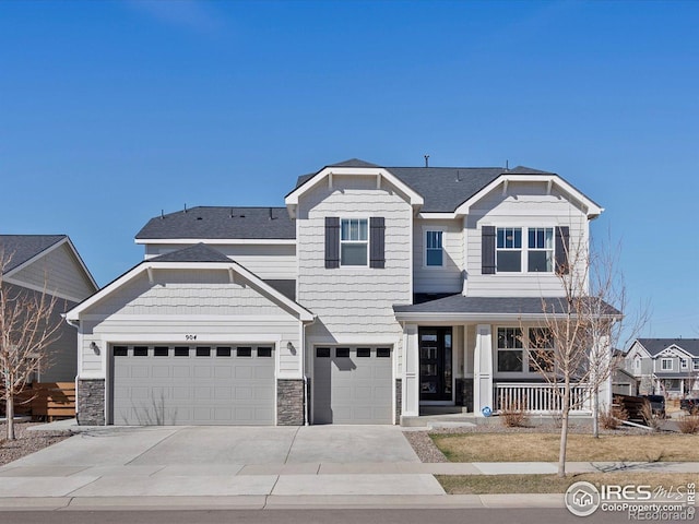 craftsman-style home with covered porch, a shingled roof, concrete driveway, and stone siding