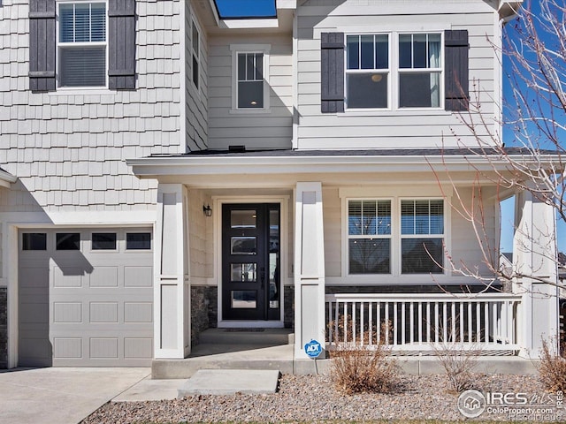 property entrance featuring covered porch, an attached garage, and driveway